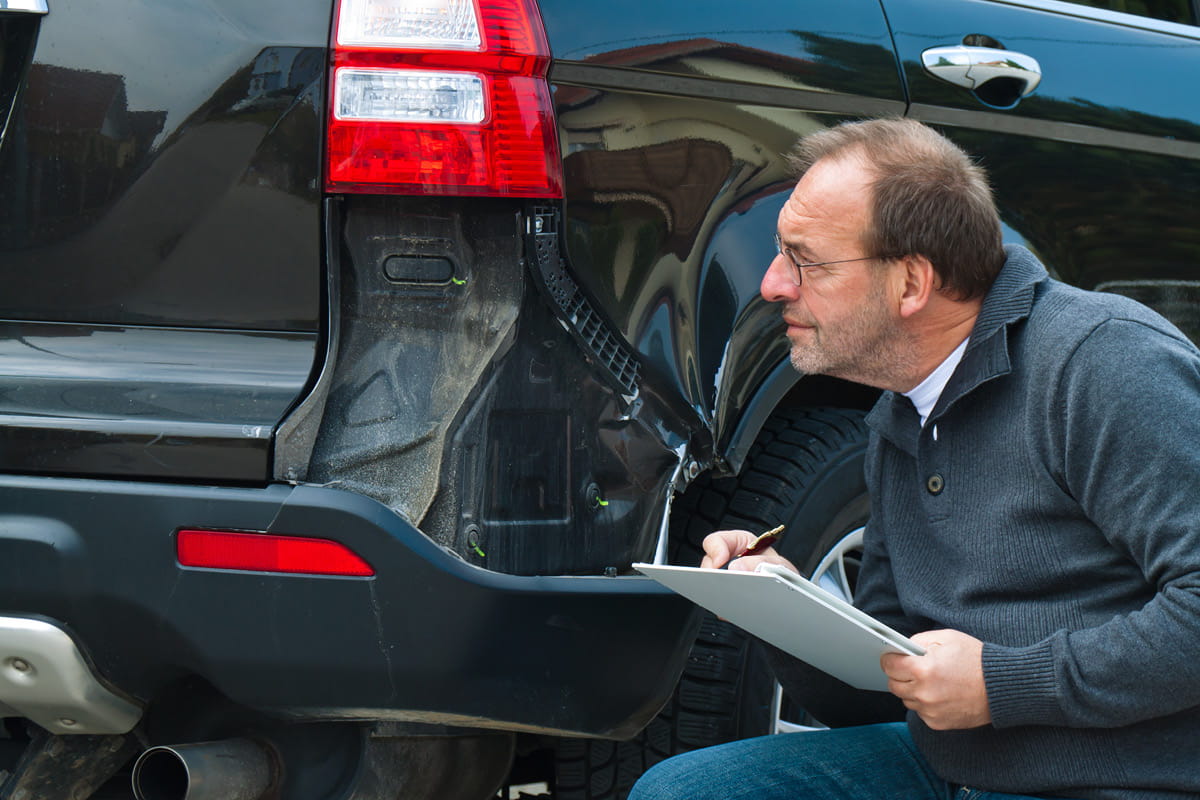 zu sehen ist ein Mann, der kniet und ein Auto begutachtet