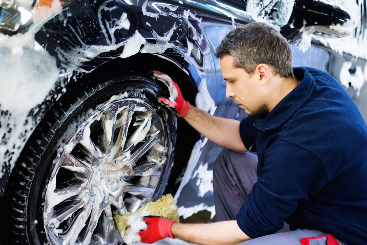 zu sehen ist ein Mitarbeiter, der ein Reifen wäscht