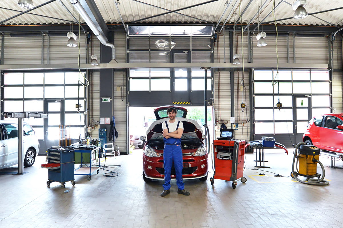 zu sehen ist ein Mitarbeiter vor einem Auto in der Werkstatt