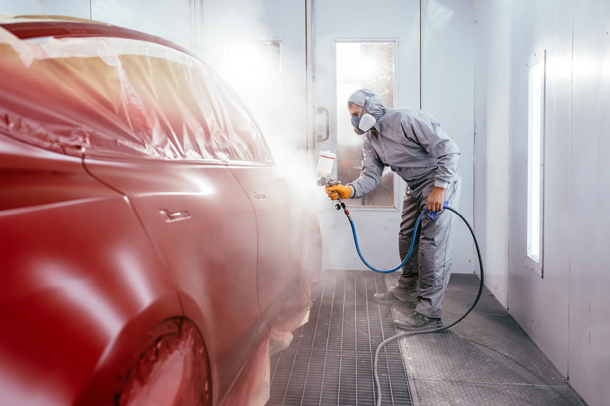 zu sehen ist ein Mitarbeiter, der ein Auto rot lackiert